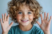 Cheerful young boy with curly blonde hair and bright blue eyes showing palms to camera, wearing turquoise t-shirt. Close up portrait against light background.