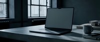 Modern laptop computer on minimalist desk in dark office workspace with large windows creating professional business atmosphere for remote work.