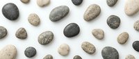 Collection of smooth river stones and pebbles in natural earth tones arranged on white background for spa, wellness and zen meditation designs.