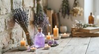 Dried lavender bundles with essential oil bottle and candles on rustic wooden table creating peaceful aromatherapy spa atmosphere for relaxation and wellness.