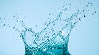 Dynamic turquoise water splash with droplets frozen in motion against a light blue background, conveying freshness and energy.