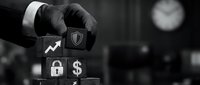 Professional businessman in suit stacking wooden blocks with financial security icons including shield, growth chart, lock and dollar symbols in monochrome setting.