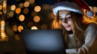 Young woman wearing Santa hat working on laptop surrounded by warm golden bokeh lights and festive decorations, ideal for holiday business and remote work concepts.
