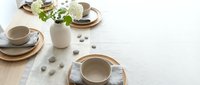 Minimalist coffee table setting with neutral ceramic cups, wooden plates and fresh greenery creating cozy morning atmosphere for lifestyle branding.