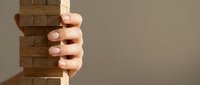 Hand holding wooden block tower, risk management and stability concept for business strategy.