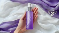 Female hand holding purple cosmetic spray bottle against white and purple silk fabric background with delicate flowers, elegant skincare product photography.