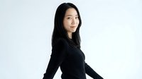 Young Asian woman in black long sleeve top posing confidently against white background. Professional portrait for business, lifestyle content.