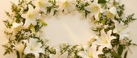 Elegant white lily and greenery wreath with delicate foliage arrangement for wedding decor, funeral tribute, or seasonal home decoration on neutral background.