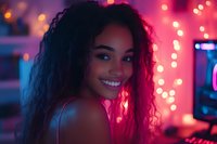 Young African American woman with curly hair smiling over shoulder in vibrant neon pink lighting with bokeh effects, creating atmospheric nightlife ambiance.