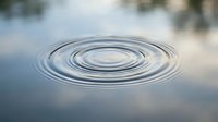 Concentric water ripples spreading across calm lake surface creating peaceful zen meditation atmosphere for wellness and mindfulness concepts.