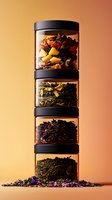 Stacked glass jars with loose tea leaves and dried flowers, black lids against warm orange background. Transparent containers show varied colors and textures of tea blends.