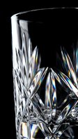 Elegant cut crystal glass with intricate diamond pattern displaying prismatic light reflections on black background for luxury dining and home decor.