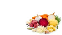 Fresh organic vegetables including beetroot, carrots, onions, potatoes and herbs arranged on white background for healthy cooking and nutrition concepts.