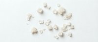 Scattered white chalk pieces and dust fragments on neutral background, suitable for educational materials, art supplies, cleaning product advertising, and creative design projects.