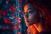 Young African American woman with curly hair and glasses in profile against digital data visualization background illuminated by red and blue neon lights.
