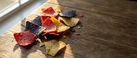 Colorful autumn leaves scattered on rustic wooden surface with warm sunlight streaming through window creating natural seasonal home decor atmosphere.