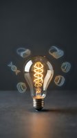 Vintage Edison bulb with glowing filament surrounded by floating DNA helixes on dark background representing genetic innovation and biotechnology research.