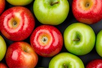 Fresh red and green apples arranged on dark background, close up view. Ripe organic fruits with glossy skin showing natural texture and vibrant colors.