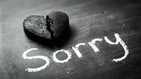 Broken heart and the word Sorry written in chalk on a dark blackboard surface, symbolizing apology, regret, and emotional pain.