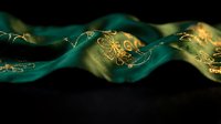 Luxurious emerald green silk fabric with ornate golden embroidered patterns flowing elegantly against dark background for premium textile design.
