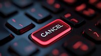 Glowing red cancel button on black computer keyboard in dark atmosphere with dramatic lighting, symbolizing emergency stop or termination of process.