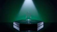 Glass trophy award on dark pedestal with dramatic spotlight illumination for recognition ceremonies and achievement presentations.