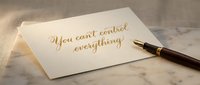 Elegant handwritten quote card with gold calligraphy saying you cant control everything next to luxury fountain pen on marble surface for mindfulness.