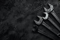 Old metal wrenches arranged on dark textured background with copy space. Minimalist industrial composition in monochrome style for repair service concept.