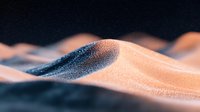 Mesmerizing sand dunes with golden and blue tones create abstract waves in desert landscape, dramatic lighting highlights natural textures and patterns in close-up view.