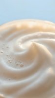 Creamy swirl texture with smooth flowing curves and soft beige tones creating organic spiral pattern for skincare and cosmetic product backgrounds.