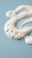 Foamy white cleanser creating bubbles on blue surface for skincare and beauty product advertising campaigns.