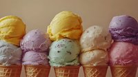 Colorful ice cream scoops in waffle cones arranged in rows showing various flavors including vanilla, chocolate, strawberry and mint on neutral background.