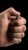 Closeup of male hand holding small metallic push button isolated on transparent background, ready for design use on t-shirts, clipart, stickers, and print-on-demand products.