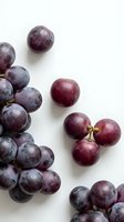 Fresh purple grapes scattered on white background, organic fruit for healthy eating, cooking ingredients, food photography and culinary design projects.