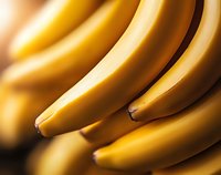 Fresh ripe yellow bananas in macro close up view showing smooth curved shapes and natural texture. Soft focus background creates depth for food photography.