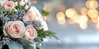 Romantic floral arrangement with soft pink roses and delicate blue flowers against blurred golden bokeh lights creating dreamy wedding atmosphere.