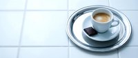 Cup of espresso with dark chocolate on white tile surface, minimalist flat lay for café, beverage, and food styling projects.
