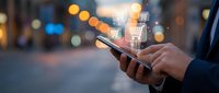 Mobile shopping app with glowing cart icon above smartphone screen held by business person on blurred city street at night for ecommerce marketing.