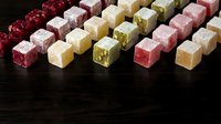 Colorful assorted Turkish delight lokum candy cubes arranged in rows on dark wooden surface, traditional Middle Eastern sweets confectionery dessert.