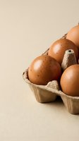 Fresh brown eggs in cardboard carton on neutral background for cooking and baking recipes.
