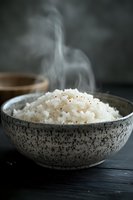 Steaming hot white rice served in rustic speckled ceramic bowl on dark wooden surface with rising steam and dramatic moody lighting for food photography.