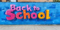 Vibrant graffiti art on blue brick wall displays Back to School text in pink and orange letters against urban backdrop, creating modern street art aesthetic for education theme.