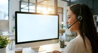 Professional female customer service representative with headset working at computer in modern office environment for business communication and support.