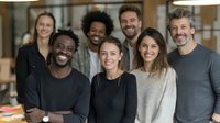 Diverse business team smiling in modern office environment, showcasing collaboration, teamwork, and professional camaraderie in corporate workplace.