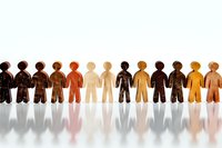 Paper cutout figures in diverse skin tones standing in row casting shadows, representing unity, diversity, inclusion and community in workplace or society.