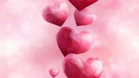 Romantic pink and red hearts floating with sparkles and bokeh effects on soft rosy background, creating dreamy Valentine's Day atmosphere. Perfect for love themes.