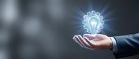 Businessman hand presenting glowing lightbulb with gear mechanism symbolizing innovation, creative solutions and business strategy development concept.