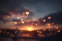 Romantic sunset sky with golden heart-shaped bokeh lights floating over blurred landscape. Love, romance and Valentine's Day concept for greeting cards.