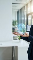 Businesswoman in formal black suit holding glowing holographic globe with digital workflow icons for creation, development, and deployment in modern office environment with natural light.