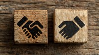 Two wooden blocks with handshake icons on rustic wood background representing business partnership, teamwork and cooperation concepts for corporate design.